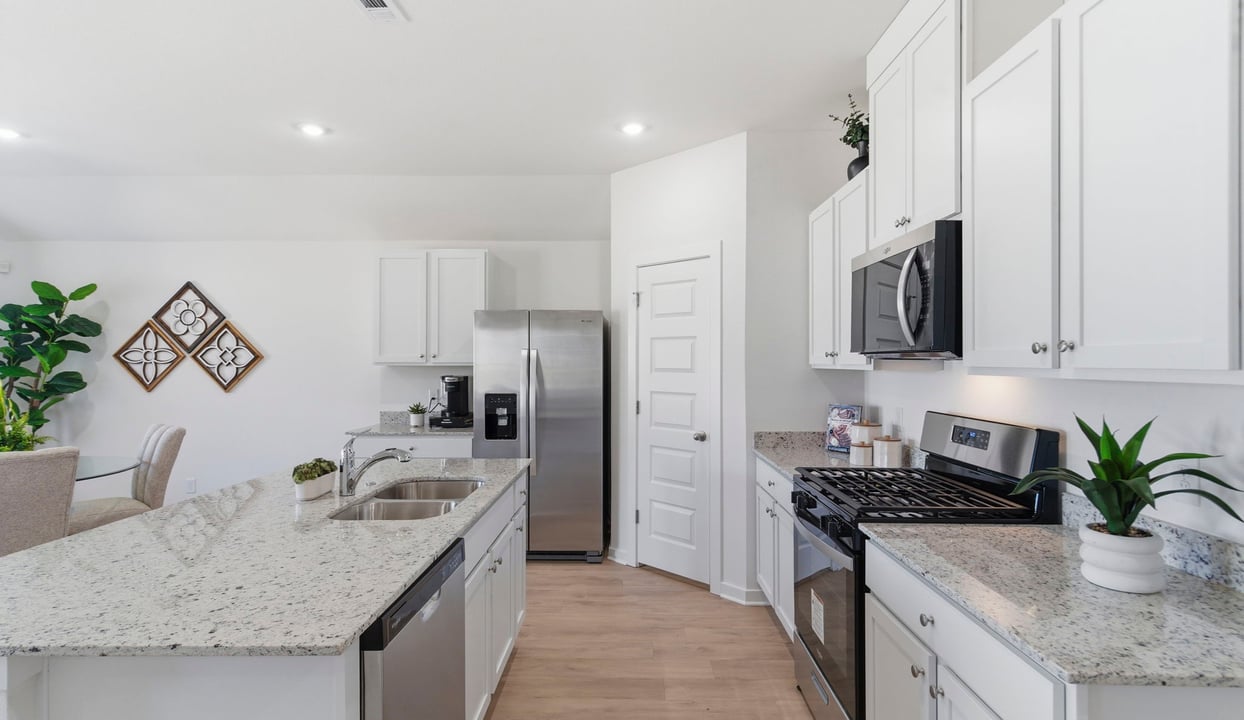 Bright and spacious kitchen with countertops, stainless steel appliances, and an island with bar seating.