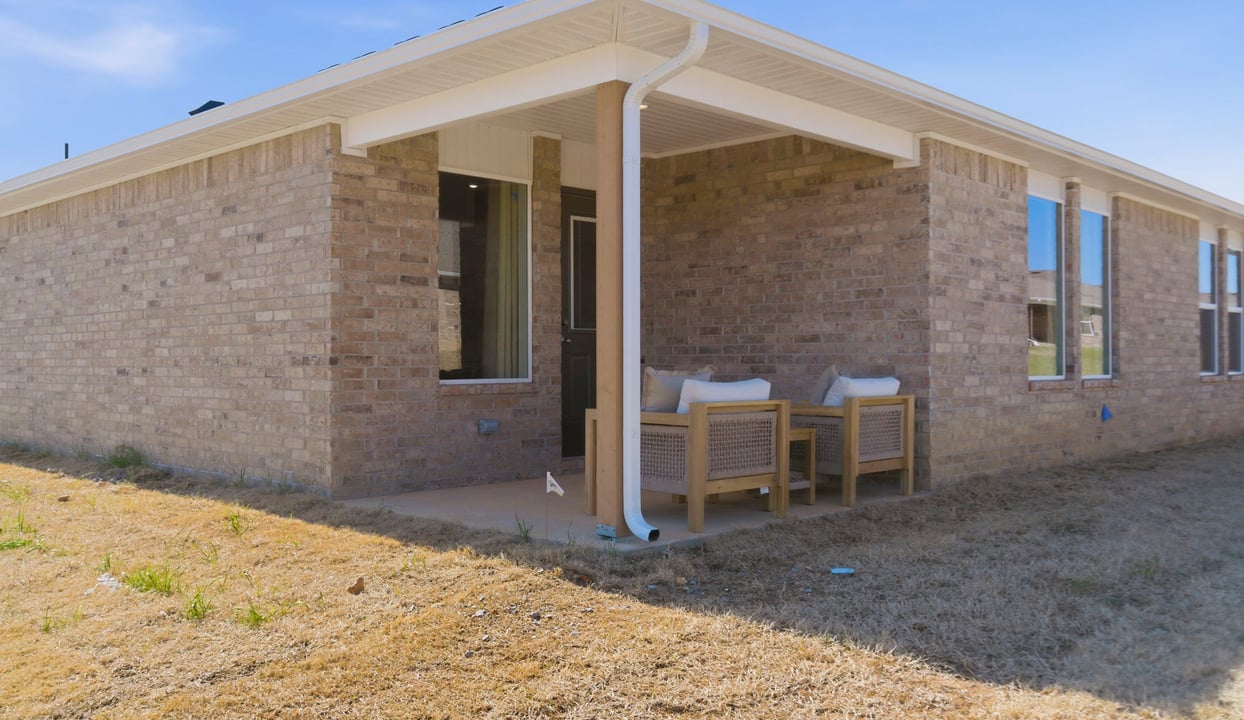 Outdoor covered patio with seating area overlooking a well-maintained lawn, perfect for relaxation