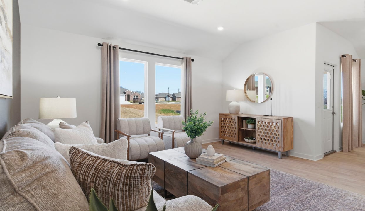 A cozy living room feature vinyl wood flooring and a view to the kitchen and dining area.
