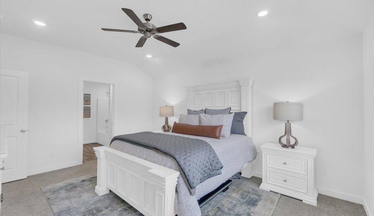 Primary Bedroom with white walls, gray carpet and ceiling van. Doorway into the master bathroom.