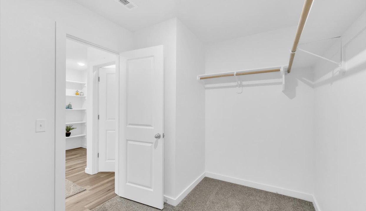 Spacious master closet with white walls and shelving