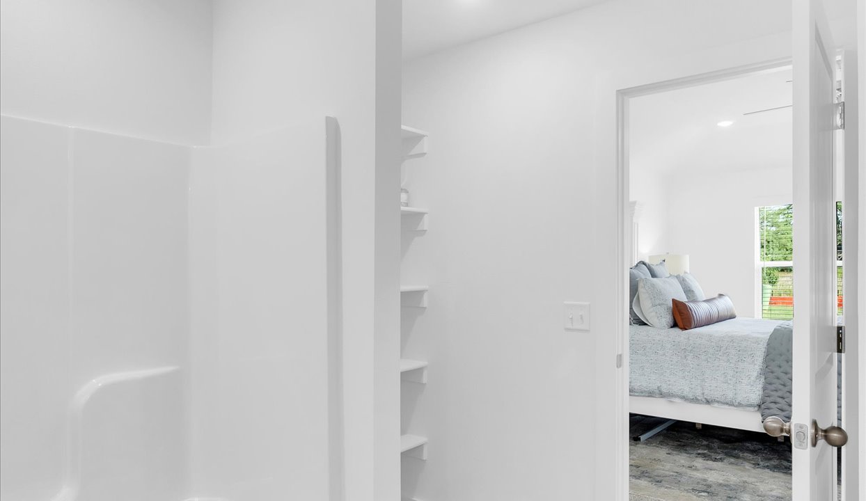 Master bathroom featuring a shower/tub combo with built in shelves. Door leading into the master bedroom.