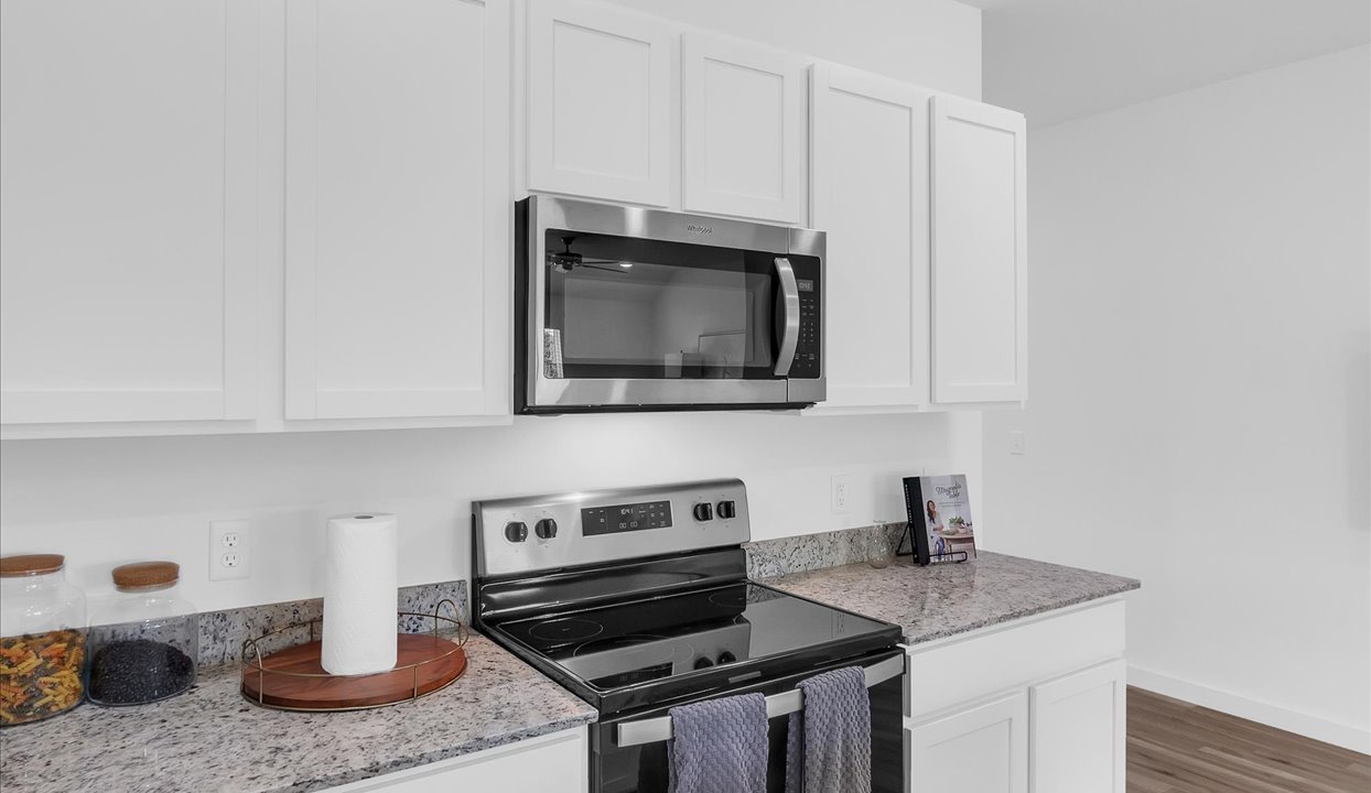 Kitchen area with white cabinets and stainless steel appliances.