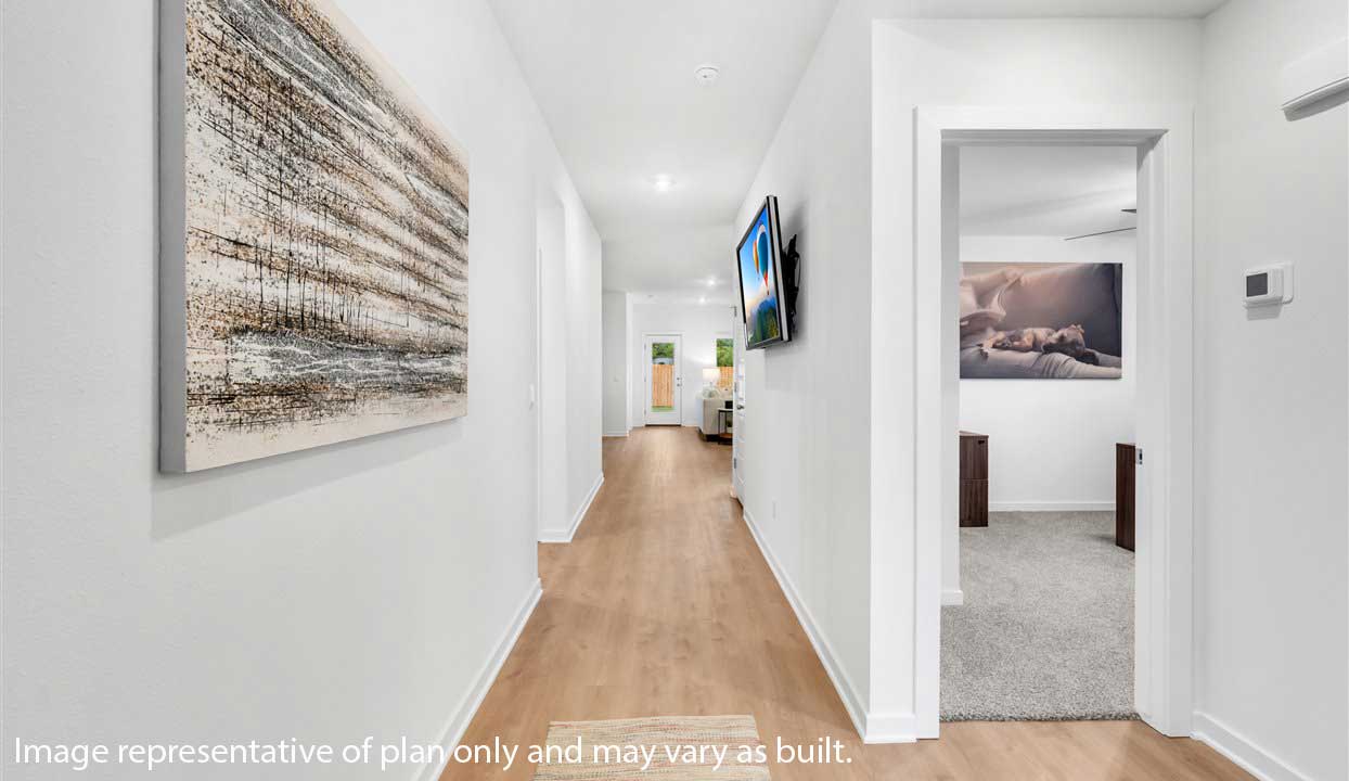 Entryway that leads into the open-concept living, kitchen and dining area with white walls and light floors.