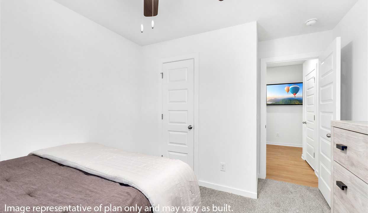 Spacious bedroom with white walls, carpet, and ceiling fan. Door leads into the hallway.
