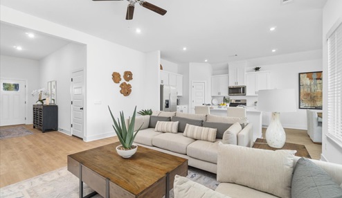 Modern open-concept living and kitchen peninsula with white cabinets and stainless steel appliances.