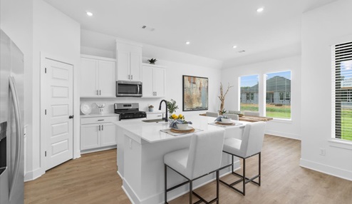 Modern open-concept living and kitchen peninsula with white cabinets and stainless steel appliances.