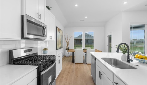 Modern open-concept living and kitchen peninsula with white cabinets and stainless steel appliances.