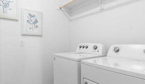 Laundry room with white shelf and washer/dryer unit.