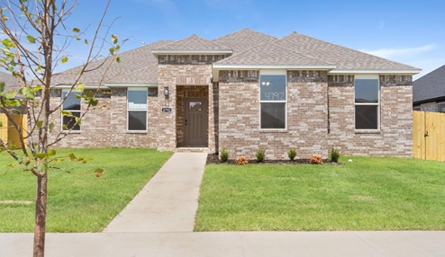 Single-story home with brown brick exterior siding with a walk-up sidewalk and landscaping.