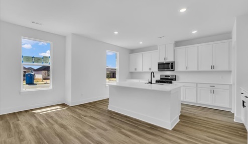 Kitchen peninsula with white cabinets and stainless steel appliances