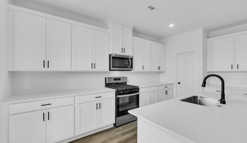 Kitchen peninsula with white cabinets and stainless steel appliances