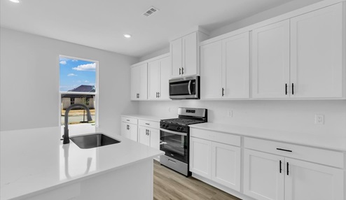 Kitchen peninsula with white cabinets and stainless steel appliances