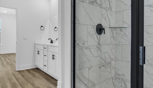Master bathroom featuring a walk in showerwith marble tile with black trim. White vanity with double sinks.
