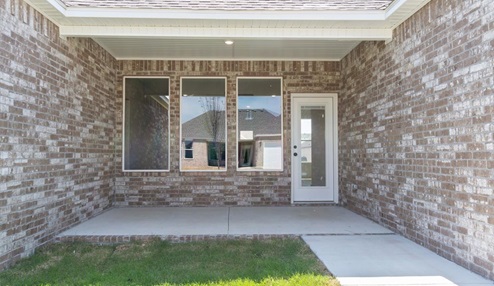 Outdoor Patio with brown brick exterior, spacious yard and driveway to two car garage.