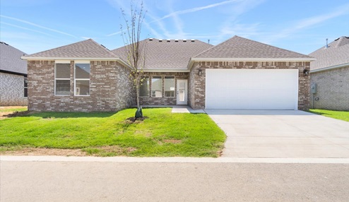 Outdoor Patio with brown brick exterior, spacious yard and driveway to two car garage.