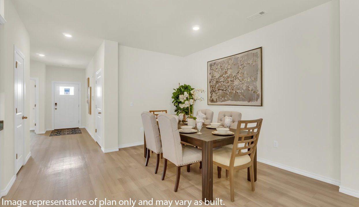 Open concept living space featuring  dinning room with hallway leading into front door.