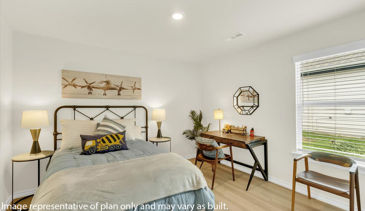 Cozy bedroom features a metal-framed bed with decorative pillows, bedside tables with modern lamps, a wooden desk with a geometric mirror, and a light wood flooring.