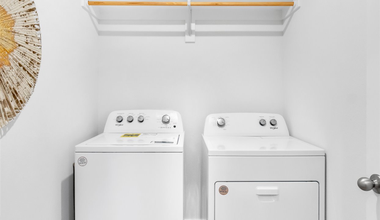 Laundry room with white cabins and washer/dryer unit.