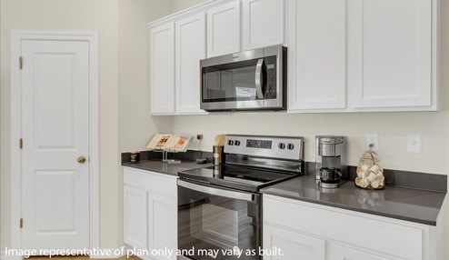Kitchen area with white cabinets and stainless steel appliances.