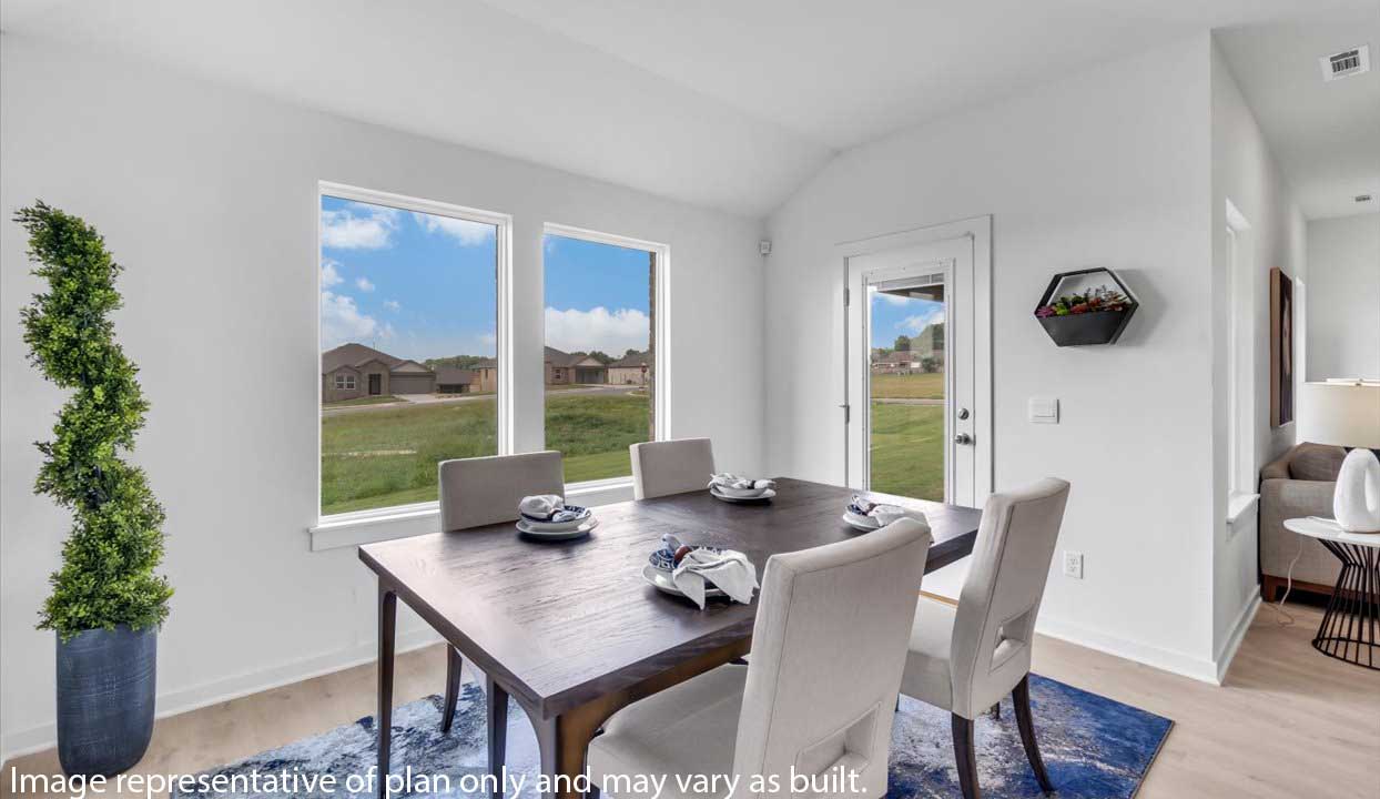 Bright dining area with a dark wood table, upholstered chairs, large windows, and a door leading outside. Decor includes a tall potted plant and wall-mounted planter.