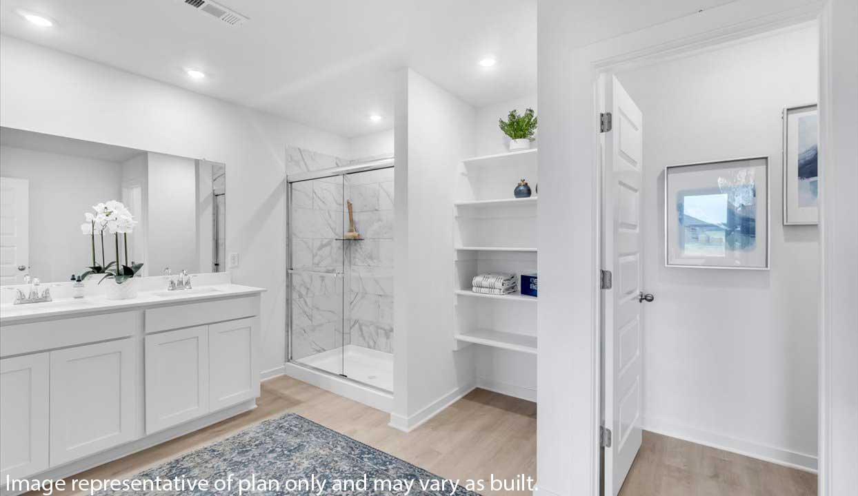 Bathroom with dual sinks, glass shower, open shelving, and a blue rug.