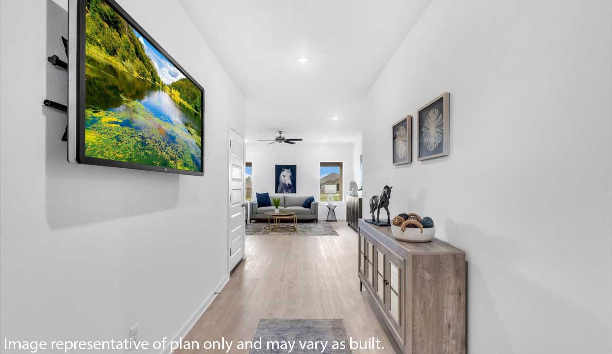Bright hallway with wood flooring, a wall-mounted TV, and a rustic console table with decor. Leads to a cozy living area with a gray sofa, blue cushions, and a horse painting.