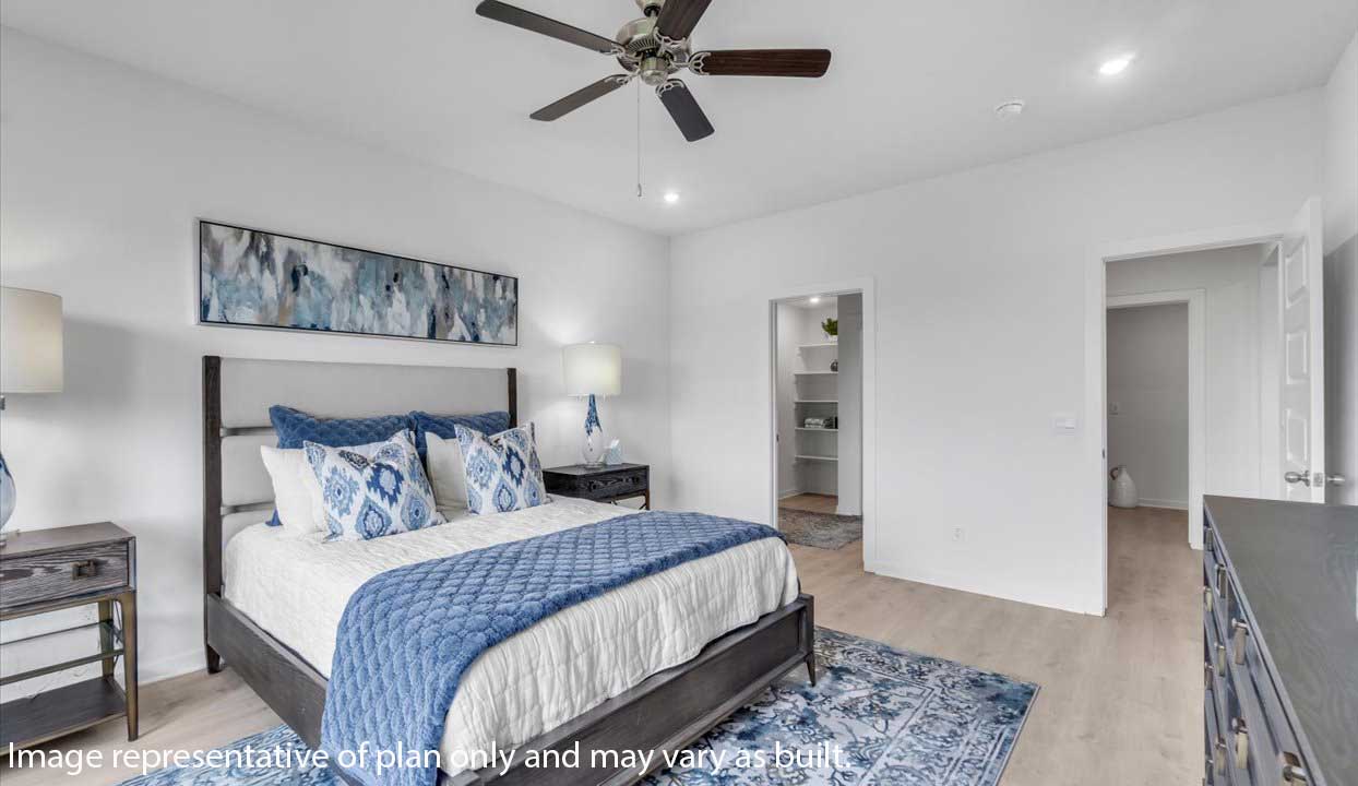 Modern bedroom with a dark wood bed frame, blue and white bedding, abstract wall art, and a ceiling fan. Room includes nightstands with lamps and an adjoining walk-in closet.