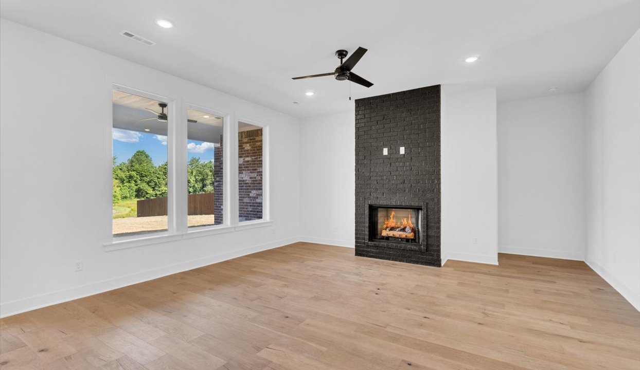 Open-concept living and dining area with white walls and light floors featuring brick wall with fireplace.