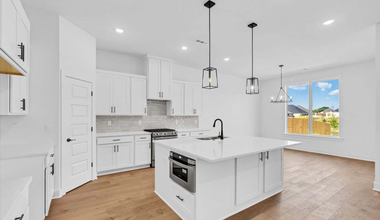 Kitchen peninsula with white cabinets and stainless steel appliances