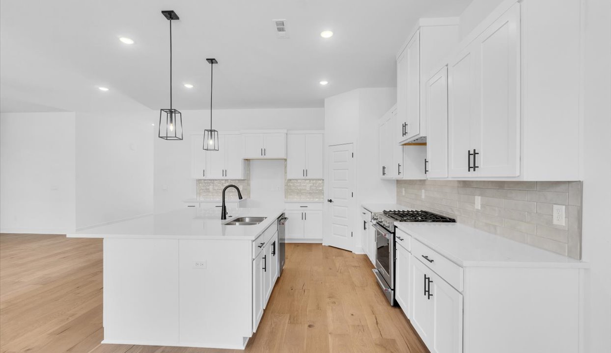 Kitchen peninsula with white cabinets and stainless steel appliances