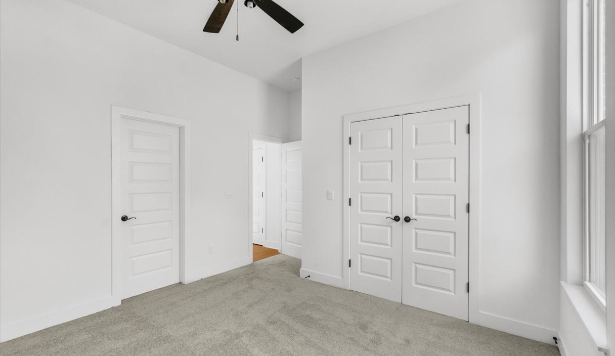 Bedroom with white walls, window and ceiling fan.