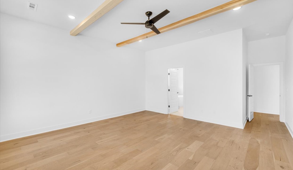 Primary Bedroom with white walls, ceiling van, wood beams, and large window.