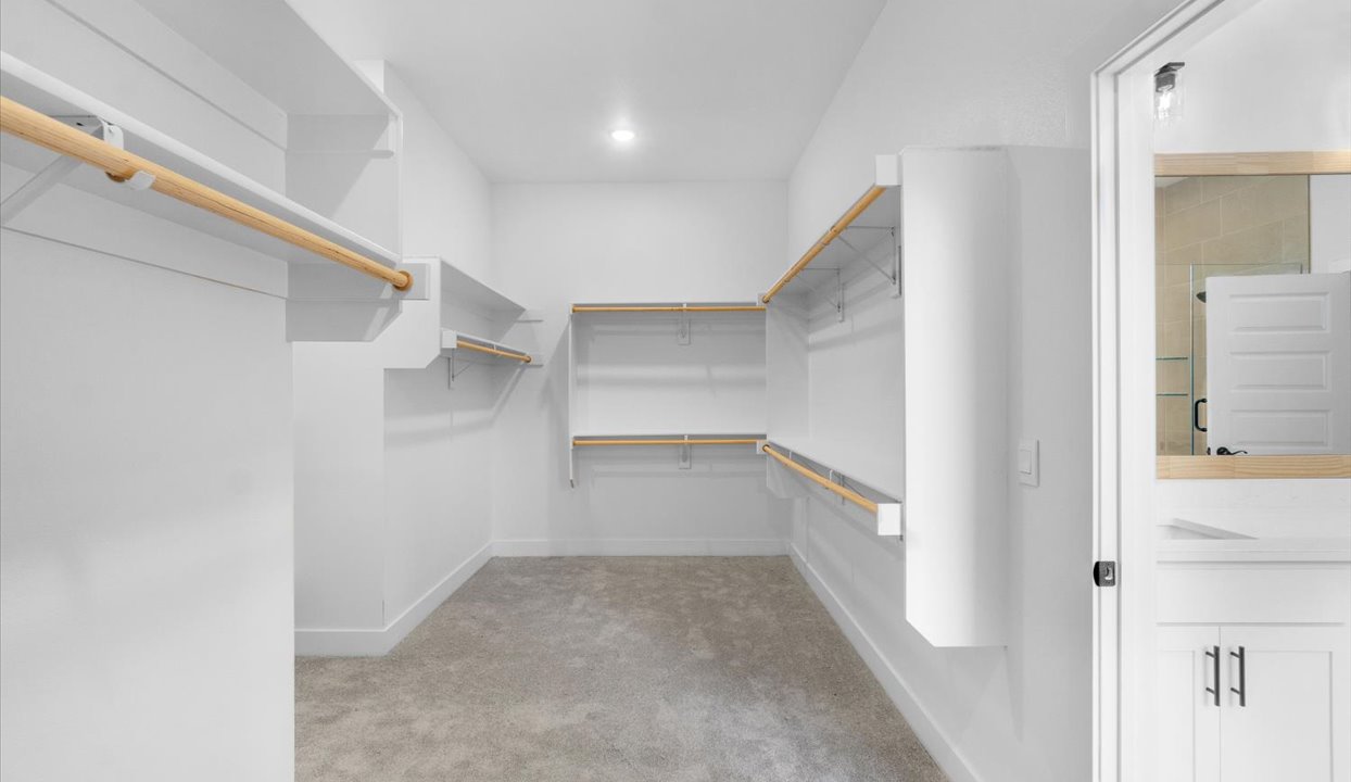 Spacious master closet with wooden shelfs.