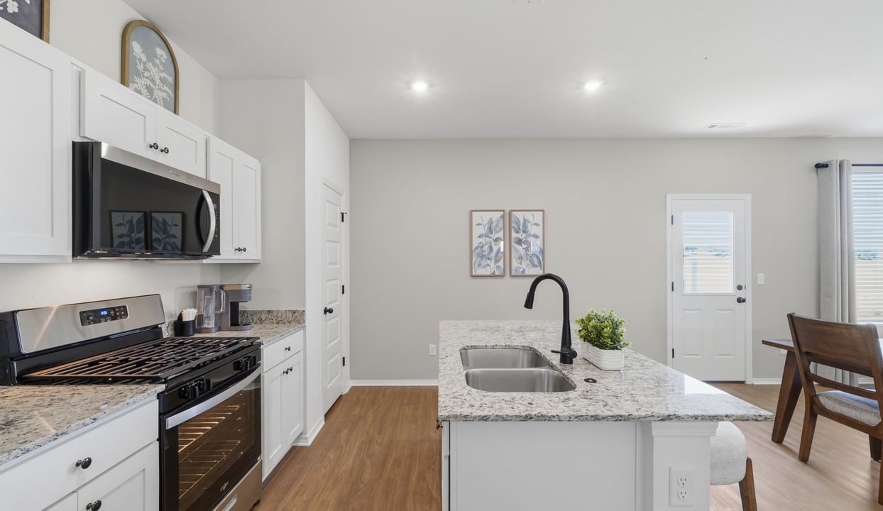Contemporary kitchen adorned with white cabinets seamlessly integrated into an open dining area layout.