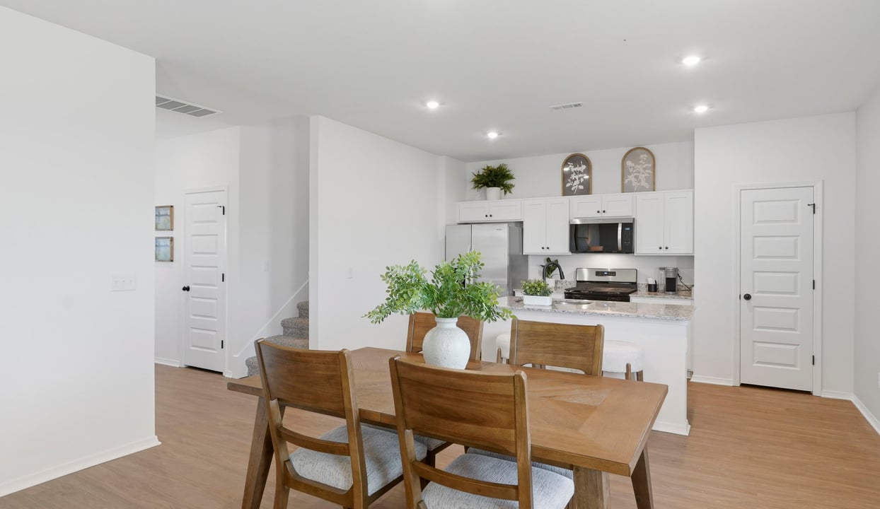 Spacious dining area with vinyl wood flooring, large window and tall ceiling.