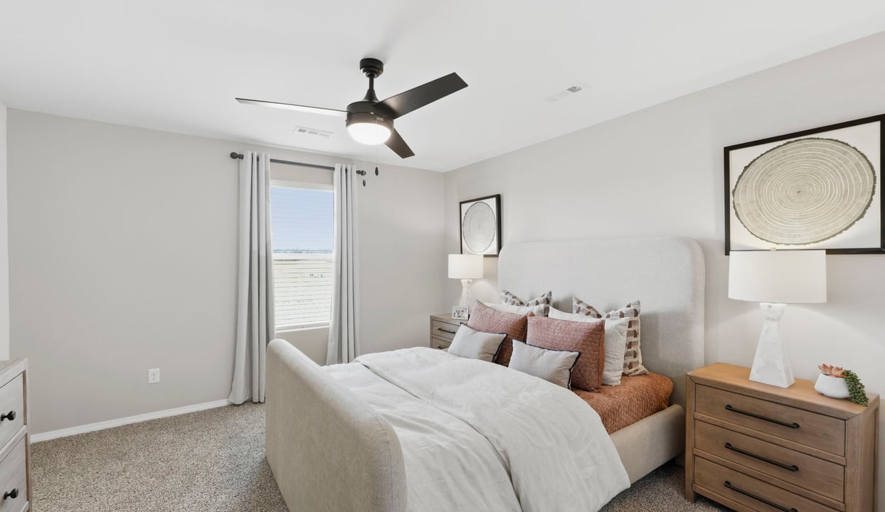 Primary bedroom with ceiling fan, plush carpeting, and a large walk-in closet.