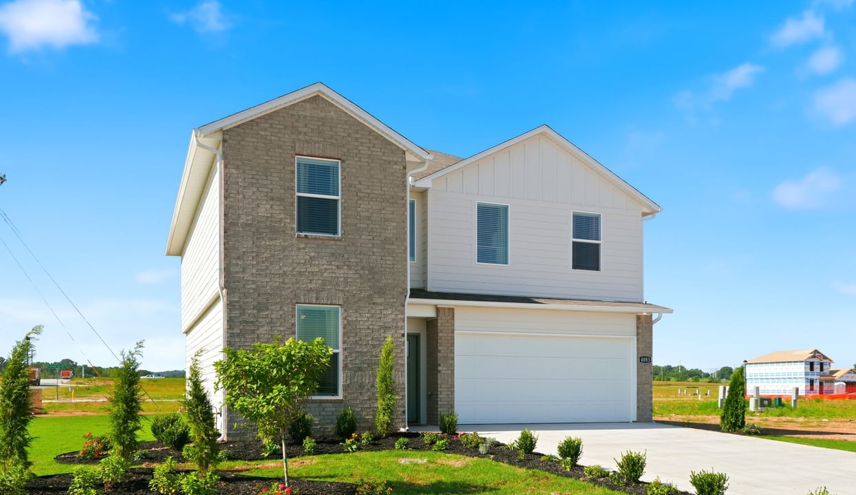 Newly built two story brick and siding home with modern architecture, a double garage, and landscaped front yard.