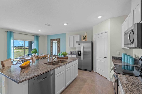 Kitchen with island seating, granite counters, spacous pantry and stainless steel appliances.