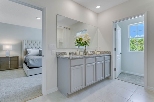 Modern bathroom with double vanity, large wall mirror, cabinets and granite countertops and walking closet