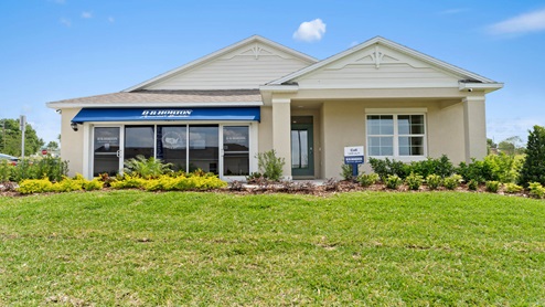 Single story new home with large windows, and grassy front yard.