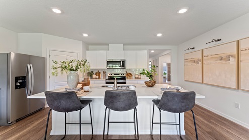 Kitchen with island seating, granite counters, spacous pantry and stainless steel appliances.