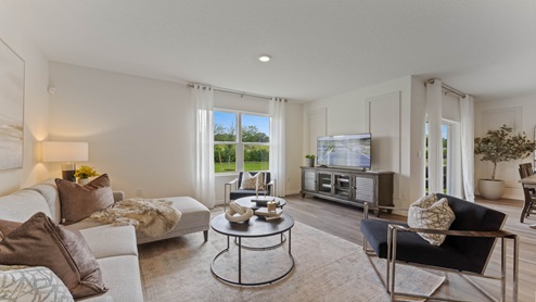 Spacious living area with couch sitting, entertainment system and natural lighting. adjacent to dining room and backyard access.