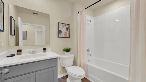 Modern guest bathroom with single vanity, large wall mirror, cabinets and granite countertops.