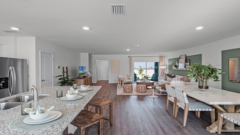 Spacious room showing living area, dining room and kitchen island with seating.