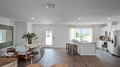 Spacious room with kitchen, and dining room table and wooded flooring.