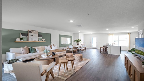 Spacious room with kitchen, living area, dining room table and wooded flooring.