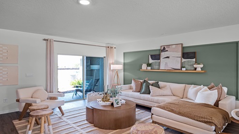Living area with couch seating and access to backyard through sliding doors.