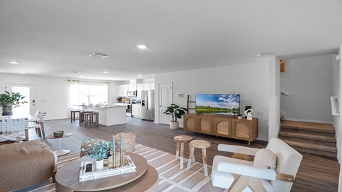 Living area with couch seating next to staircase, overseeing kitchen.