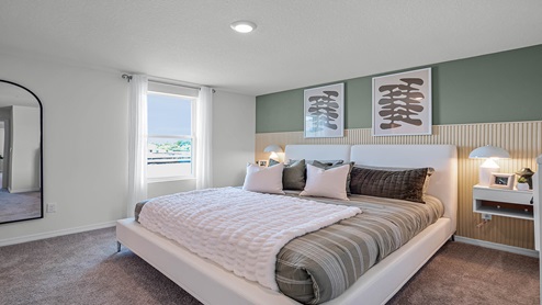 Spacious primary bedroom with king size bed, carpet flooring, natural lighting.